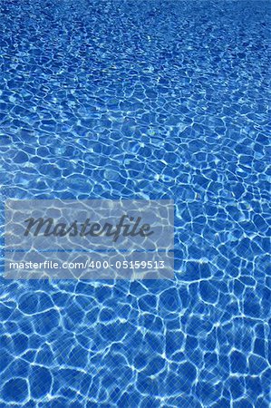 Blue water texture, tiles pool in sunny day with light reflections