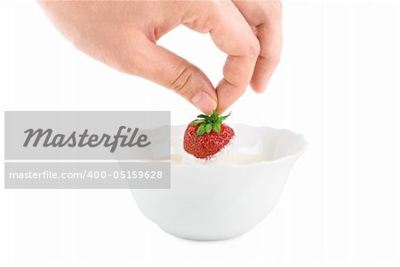 Hand with strawberry in cream on white