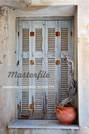 Weathered window shutter and decorative pottery. Traditional Greek island house detail.