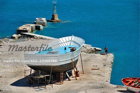 Wooden boat and fisher man at a shipyard in the harbor of Zakynthos, Greece.