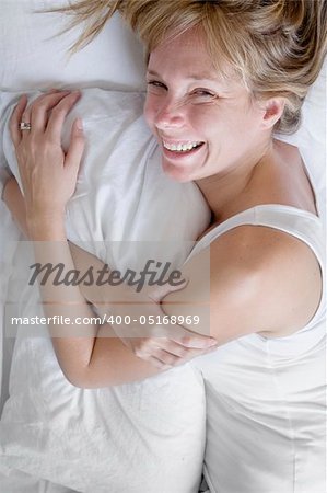 Woman in bed wrapped in white sheets