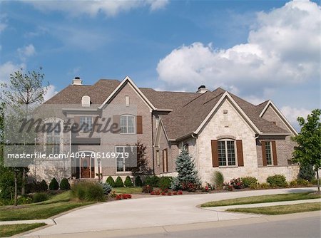 Two story brick and stone residential home with circle driveway.