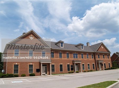 Two story red brick office building with parking spaces.