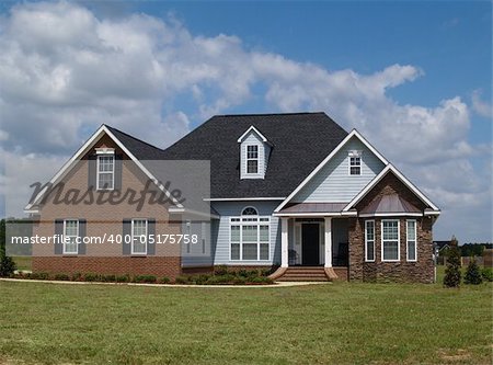 Two story residential home with brick, stone and board siding on the facade.