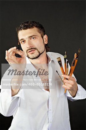 creative artist in a white shirt on a black background with a brush