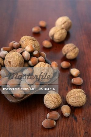 Wooden bowl with hazelnuts and walnuts on a wooden table. Shallow DOF
