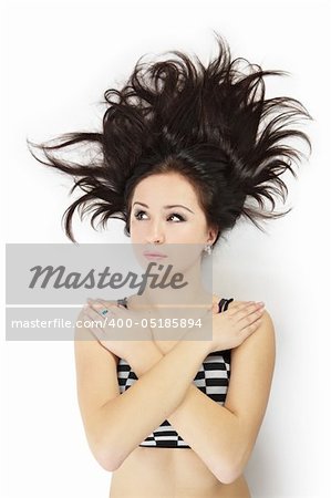 An attractive girl in a dress with a checkered pattern lies on the floor. isolated over white. black hear