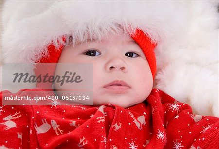 baby in santa costume on white blanket