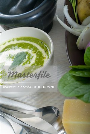 fresh spinach soup on a white bowl with sage and cream on top