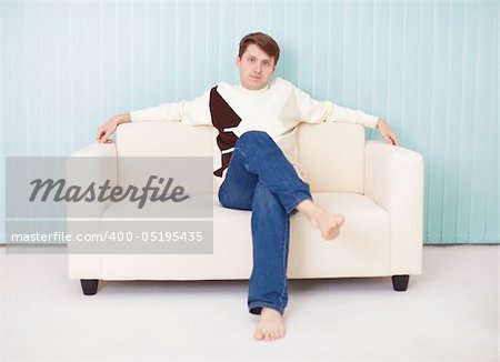 A young man sits comfortably on a soft sofa