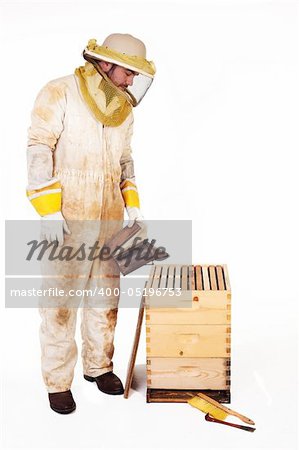 an isolated beekeeper in protection gear smoking a hive