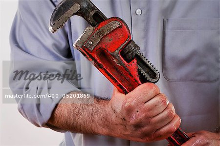 Stock image of plumber in uniform holding pipe wrench.