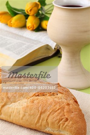 Chalice with red wine, bread, Holy Bible and tulips