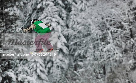 young boys jumping in air ind showing trick with snowboard at winter season