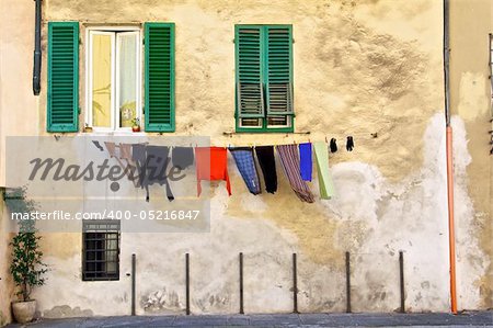 Washing hanging up to dry below two green, shuttered windows.