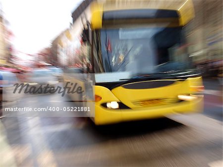 Color photo of a yellow bus on a city street