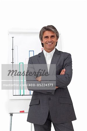 Charismatic mature businessman with folded arms in front of a board
