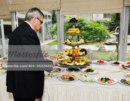 table on catering and buffet party on business seminar conference or wedding with man who choosing meat for eat and bring it in dish