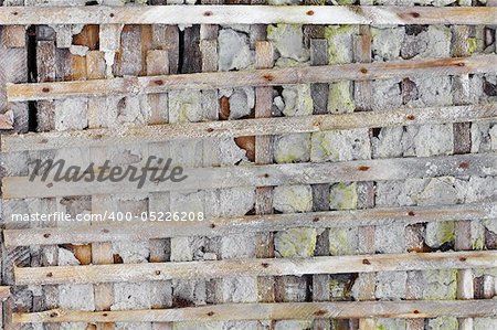 Concrete ruined wall, reinforced wooden lattice - background