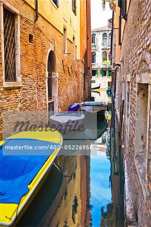 narrow canal with boats in Venice, Italy
