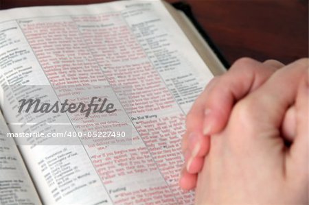 Clasped female hands on the Bible open on the text in Matthew about the Lord's prayer. Focus on the Lord's prayer text.