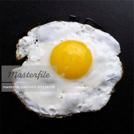 Fried egg over black textured plate background