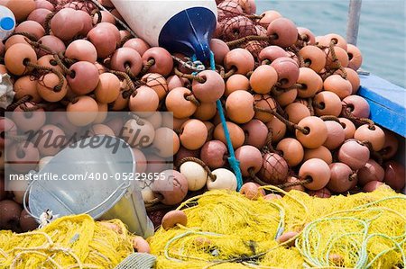 Nylon yellow  fishing net, metal bucket, buoy close-up on the boat desk