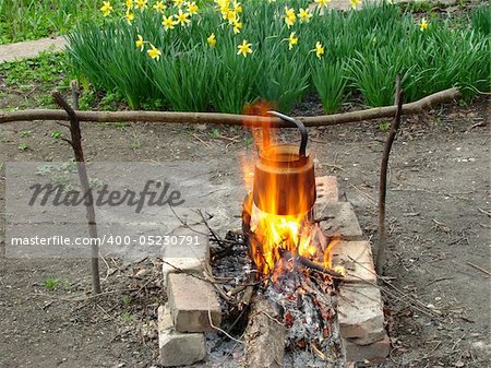 boiling water in old sooty kettle on the hiking campfire