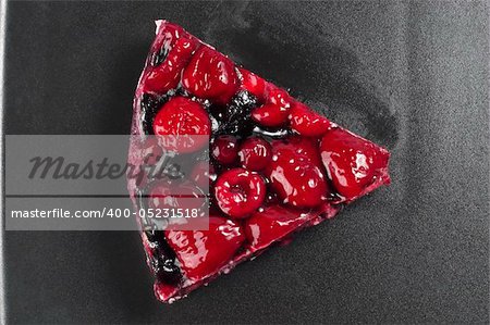 Small berries tart piece macro shot over black background