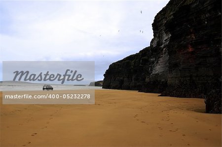 four wheel drive car on ballybunion beach with cliffs in background