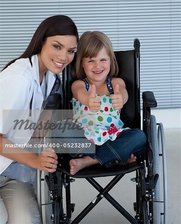 Portrait of a little girl on a wheelchair with her doctor smiling at the camera
