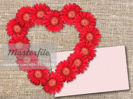 Bouquet of red flowers as heart-form with message-card on  textile background. Close-up. Studio photography.