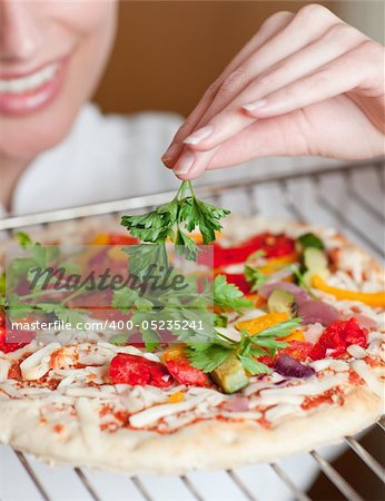 Close-up of a female chef preparing a pizza in a kitchen