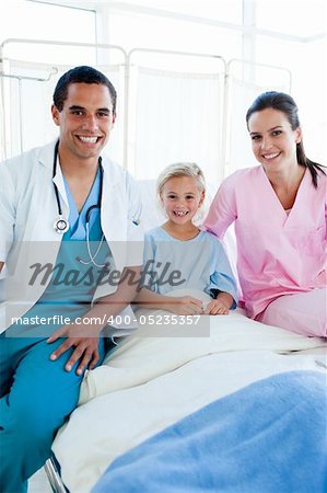 A doctor and a nurse with their little patient smiling at the camera