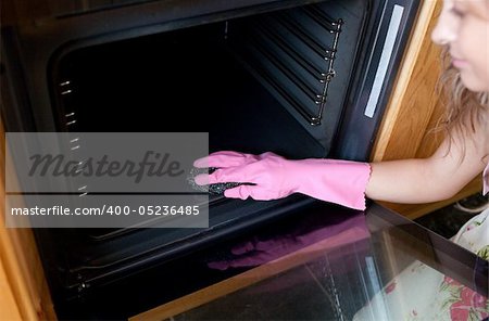 Close-up of a woman cleaning the oven in the kitchen