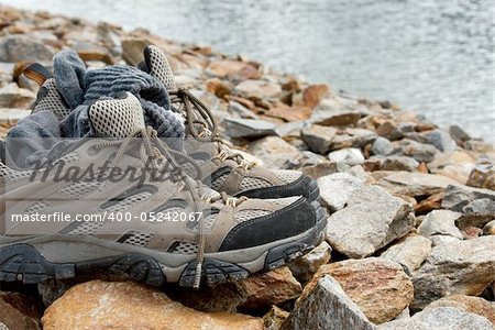 Shoes and sock on the rocks near a mountain lake