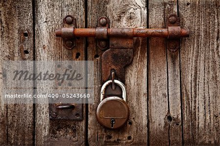 Old latch with padlock on gatees