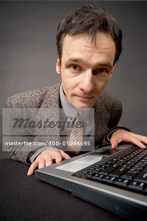 Amusing portrait of the young man on a workplace at dark office