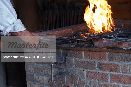 Blacksmith works on a heart trivet at the hearth