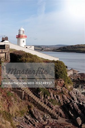 lighthouse during a sunny day on the rocks in with steps to beach in youghal county cork ireland