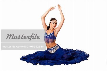 Beautiful Israeli Egyptian Lebanese Middle Eastern belly dancer performer in blue skirt and bra with arms in air sitting, isolated.