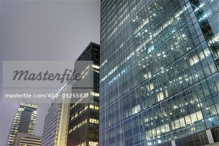 Modern building exterior with skyscraper and office in night.