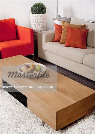 Living-room with the classic couches and wooden table with artificial fruits in basket