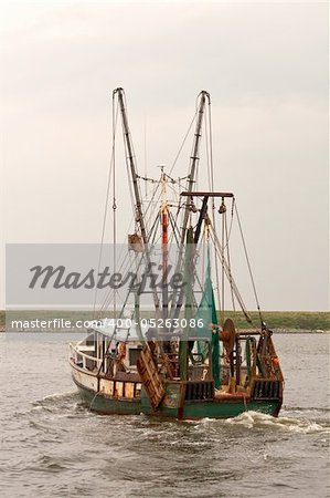 View of the stern of a fishing trawler on Pamlico Sound, North Carolina against a gray sky vertical