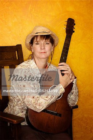 Pretty western woman in antique rocking chair with guitar