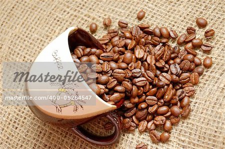 Coffe beans strewed from cup into sacking