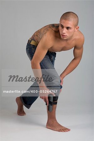 A young, muscular brazilian man in a studio shot on a gray background.