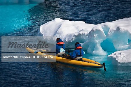 Two men in a canoe among icebergs in Antarctica