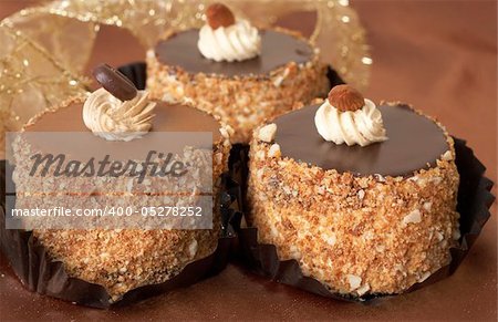 Miniature chocolate meringue cakes with cream, chocolate coffee bean and almonds