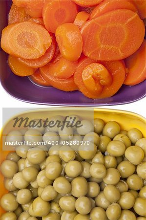 Macro background image of vibrant peas and carrots in colorful bowls.